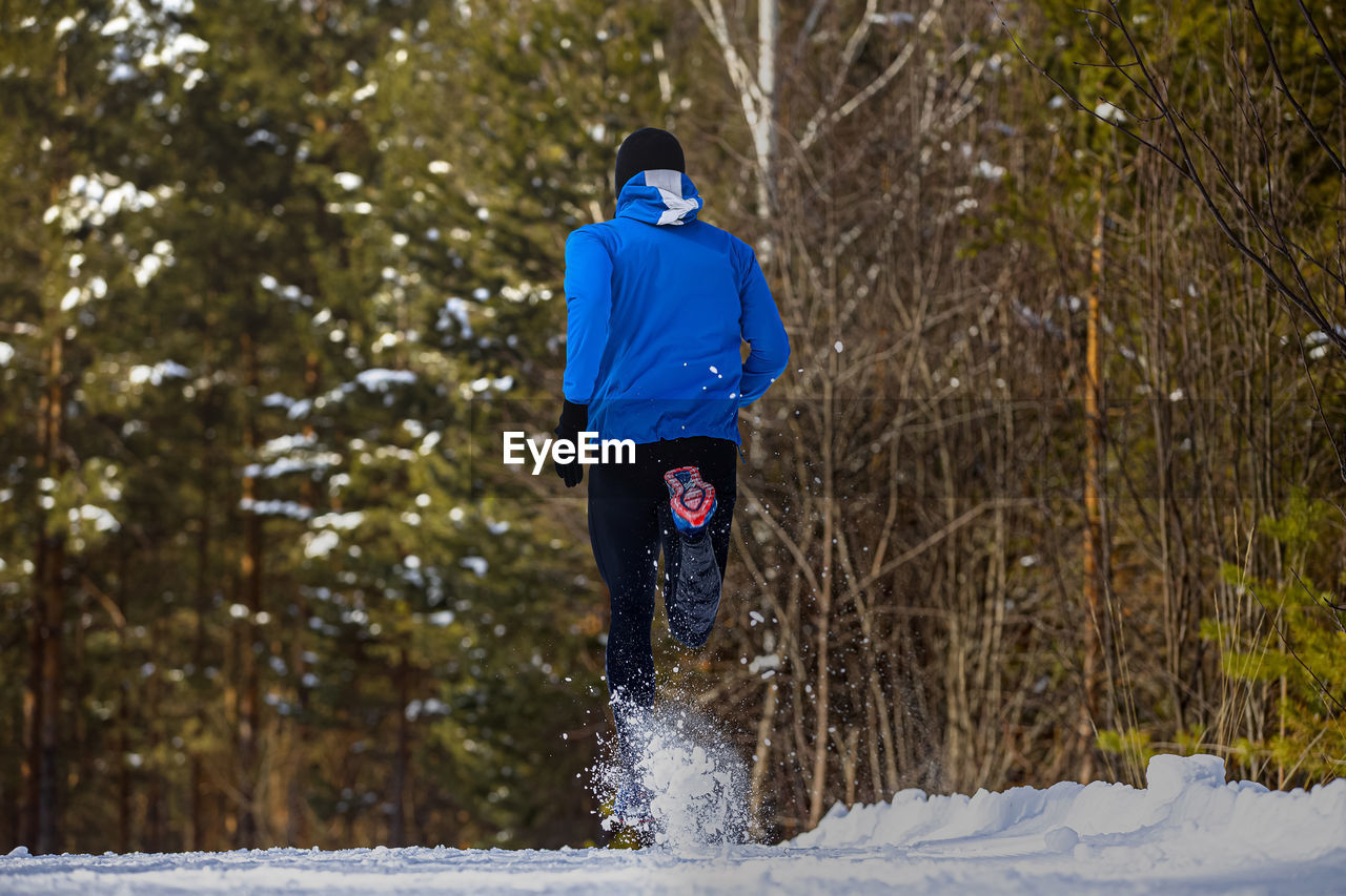 Back runner athlete running winter forest trail