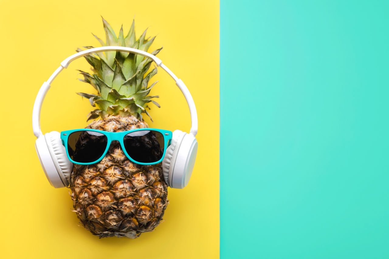 pineapple with sunglasses and hat and eyeglasses on blue background