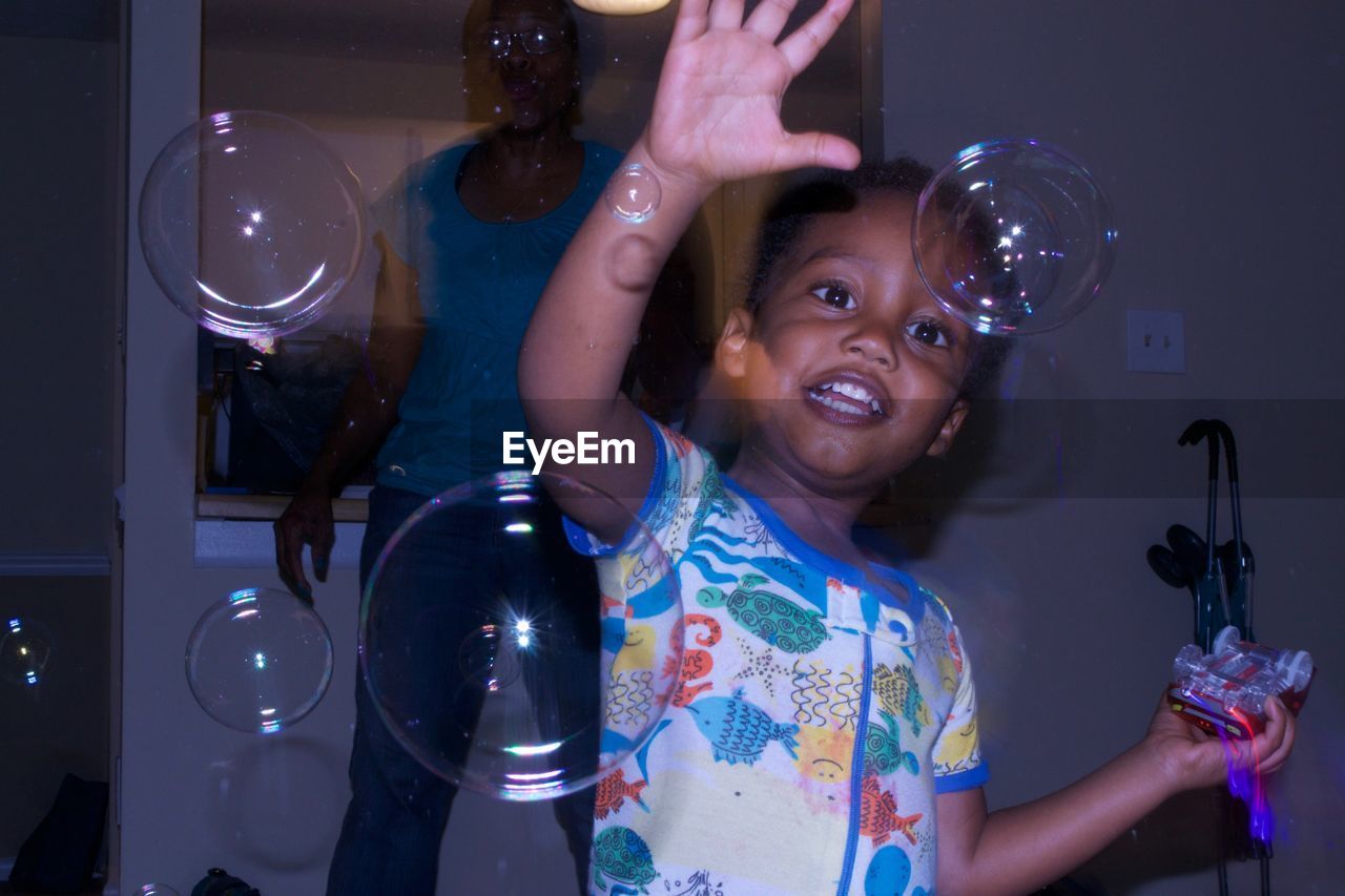 Happy girl playing with bubbles at home