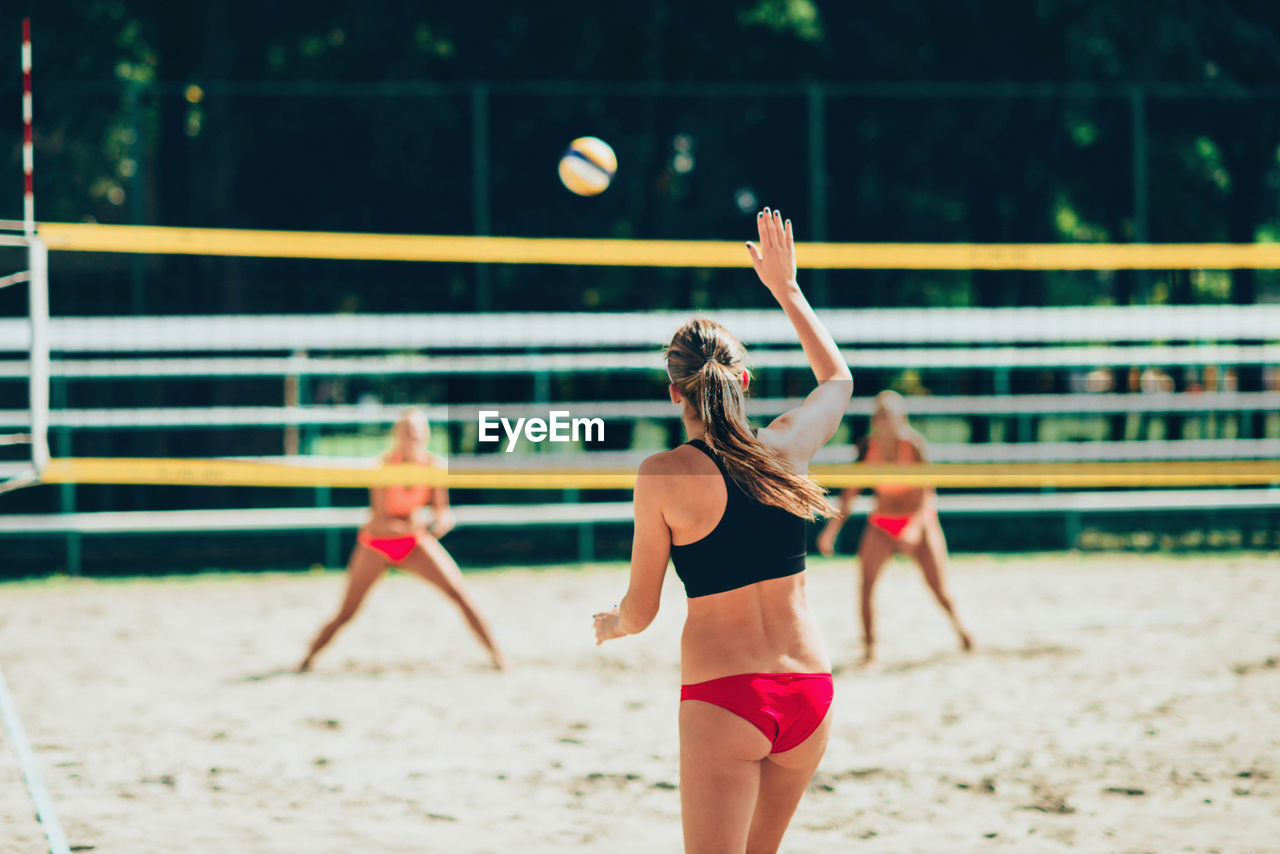 Rear view of woman playing beach volleyball