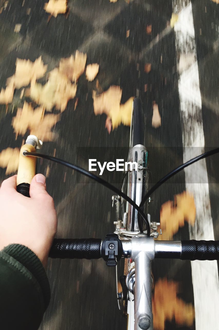 CLOSE-UP OF HAND HOLDING BICYCLE ON METAL