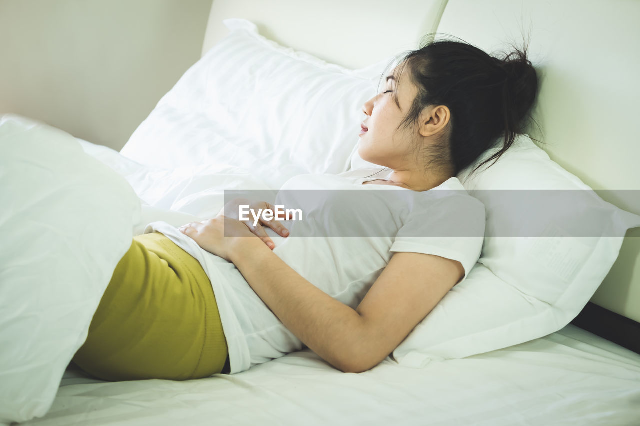Woman with stomachache lying on bed