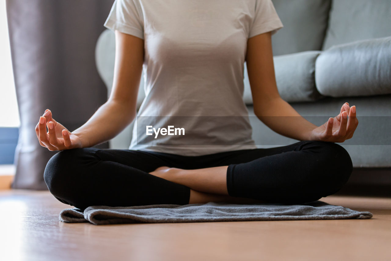 Crop unrecognizable young woman doing yoga at home