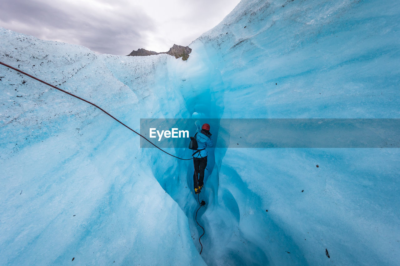 Rear view of person walking in ice cave