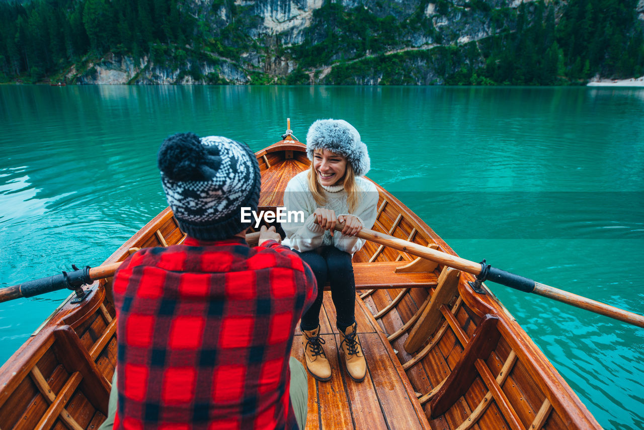 Smiling woman with man sitting in rowboat at lake