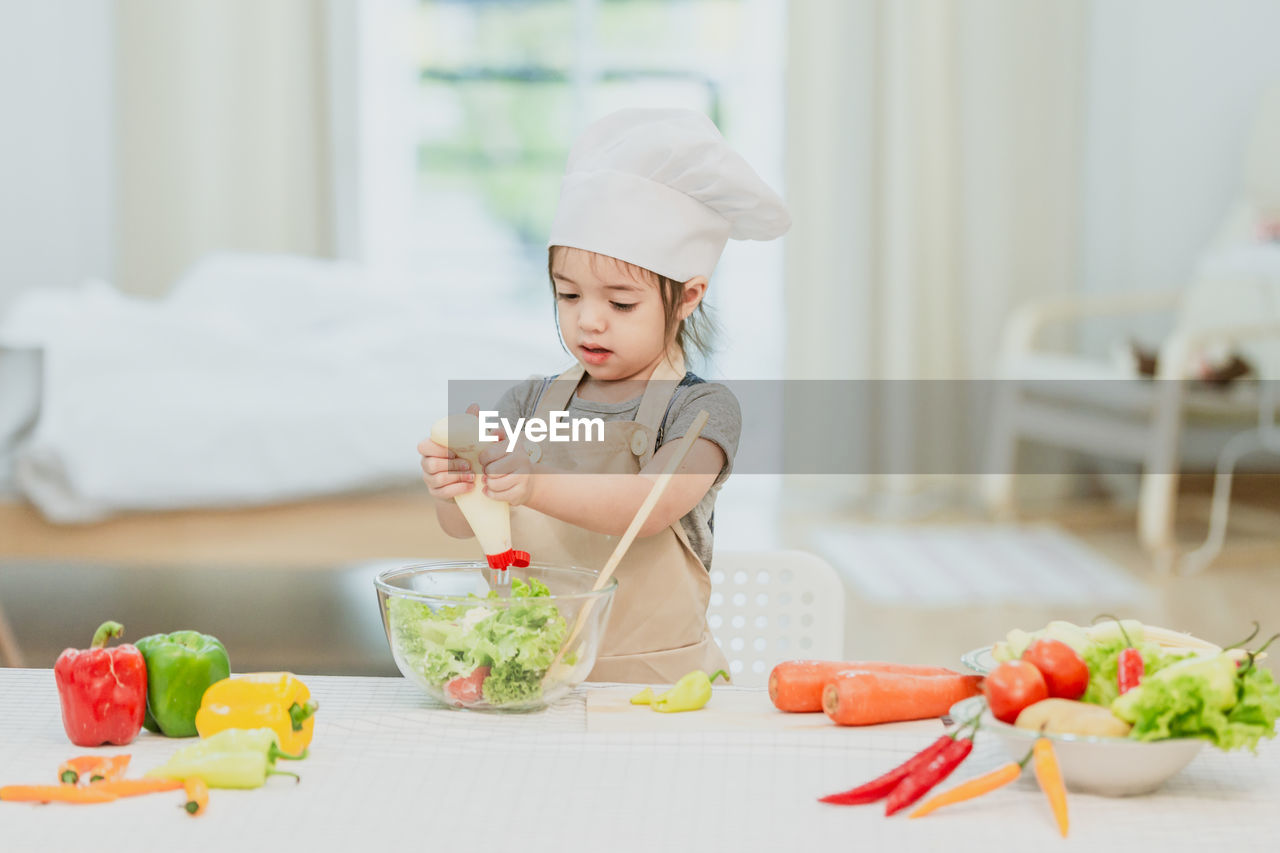 CUTE GIRL HAVING FOOD ON TABLE AT HOME