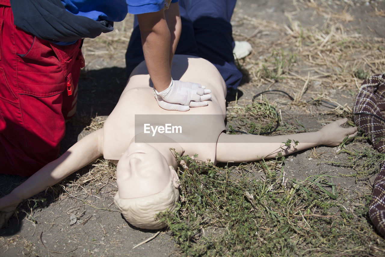 Midsection of man practicing cpr on dummy on field