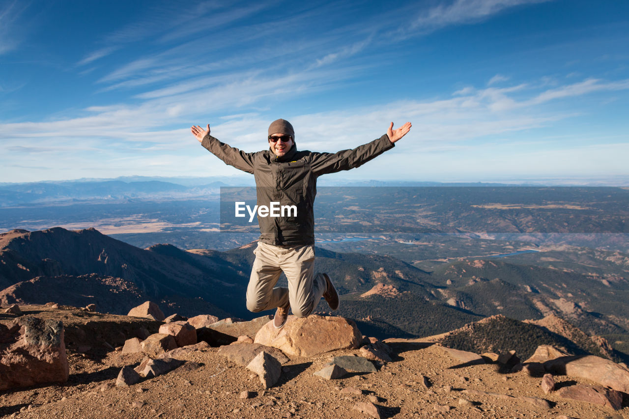 Full length of man jumping in the air and enjoying beeing on top of pikes peak, colorado against sky