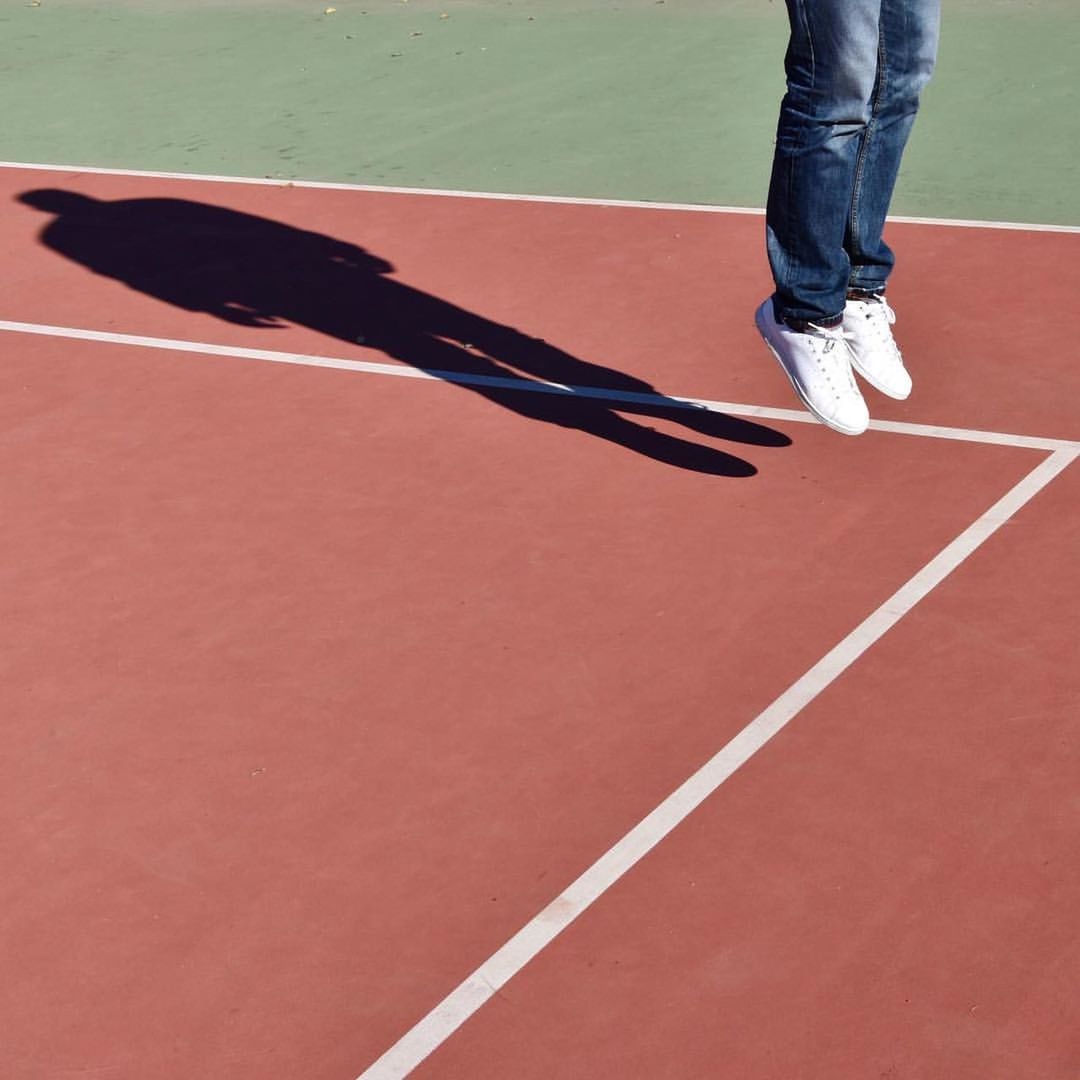 Low section of man jumping on tennis court