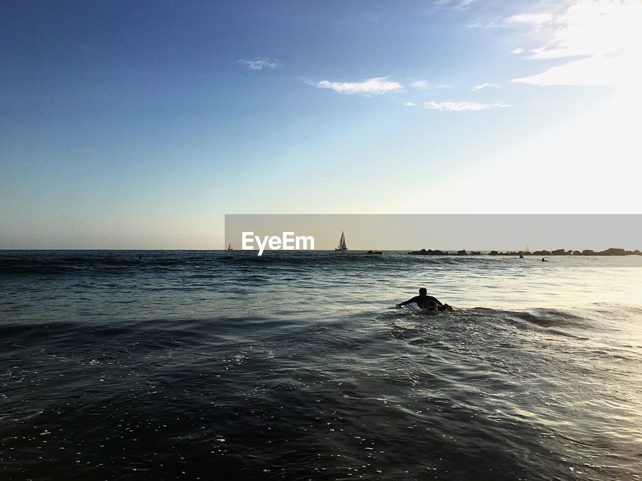 Silhouette person swimming in sea against sky