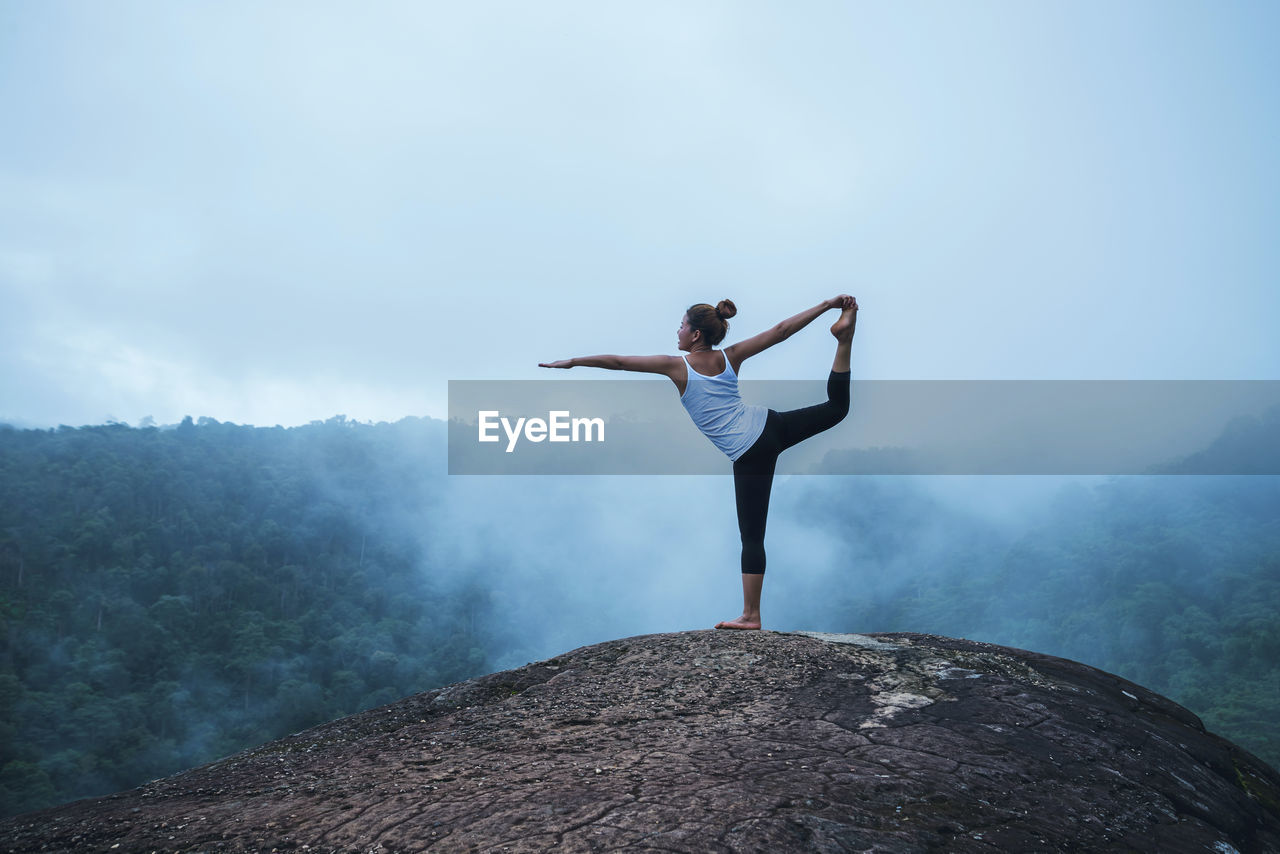 Full length of woman doing yoga on mountain against sky 