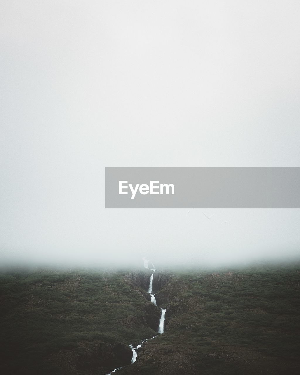 Scenic view of land against sky in foggy weather