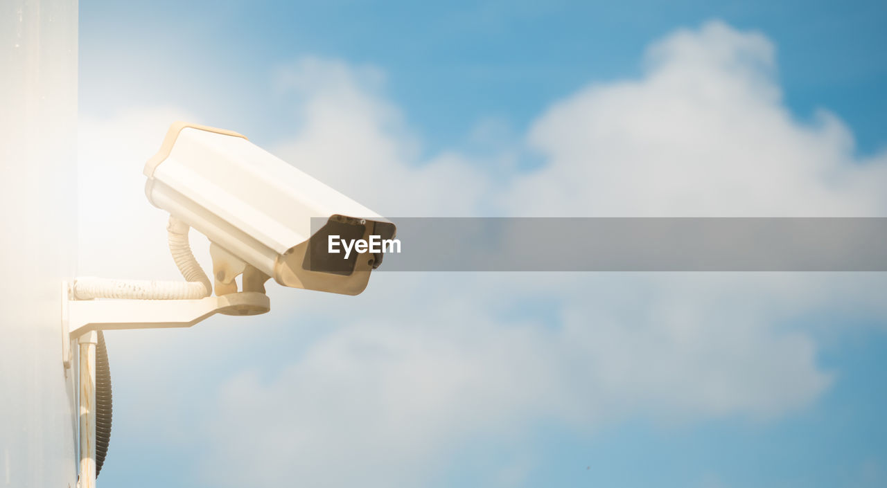 Low angle view of security camera against cloudy sky