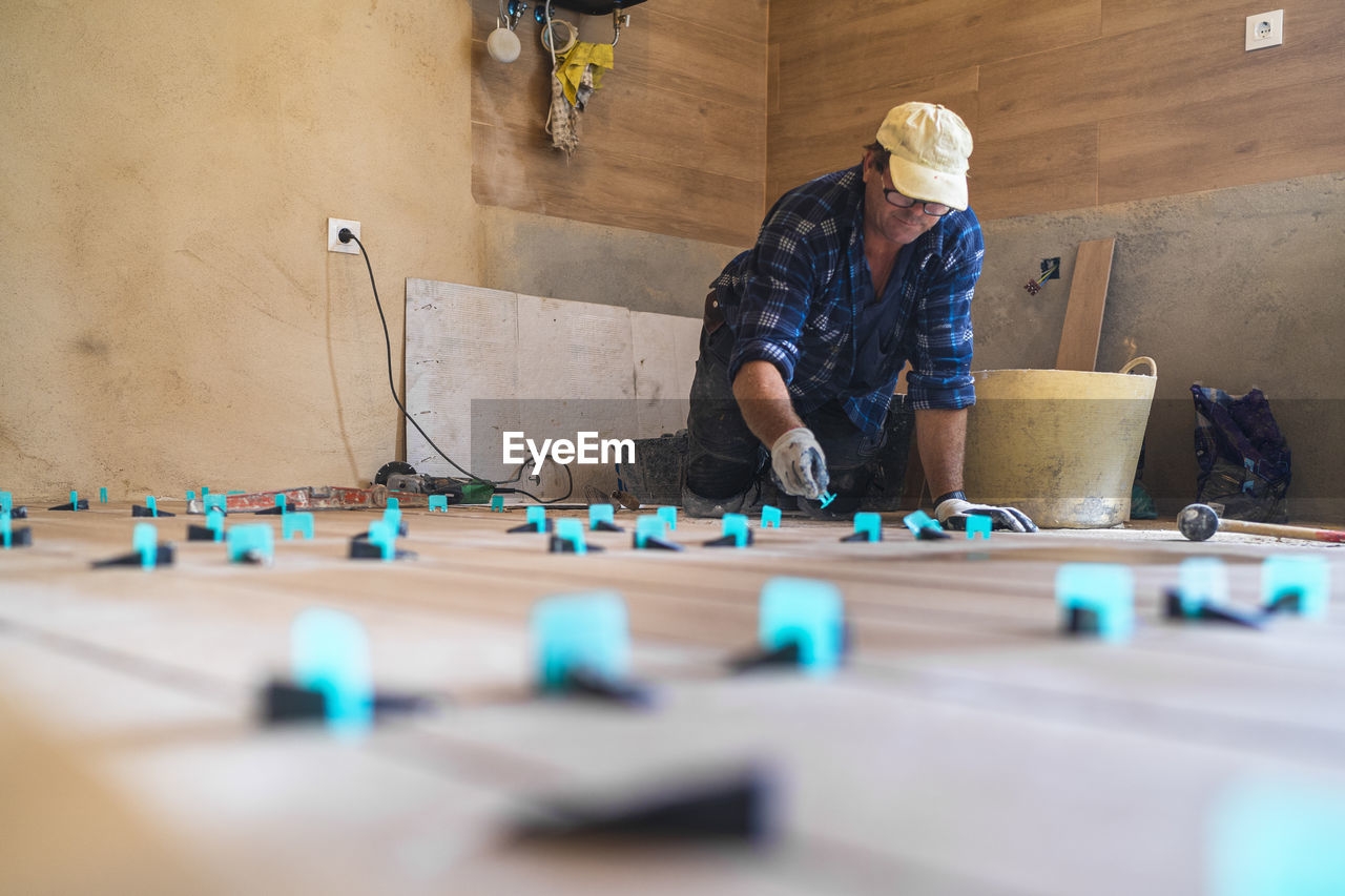 Mature man working on parquet floor in house