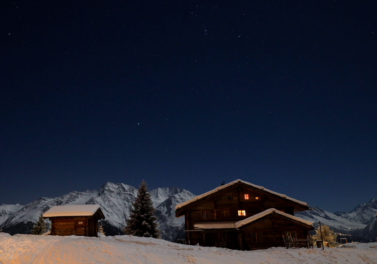 Snow covered houses against clear sky at night