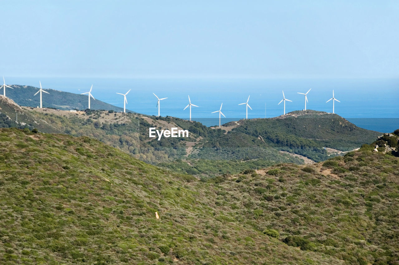 Wind turbines on field against sky