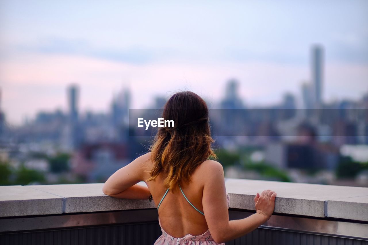 Rear view of young woman looking at cityscape from balcony