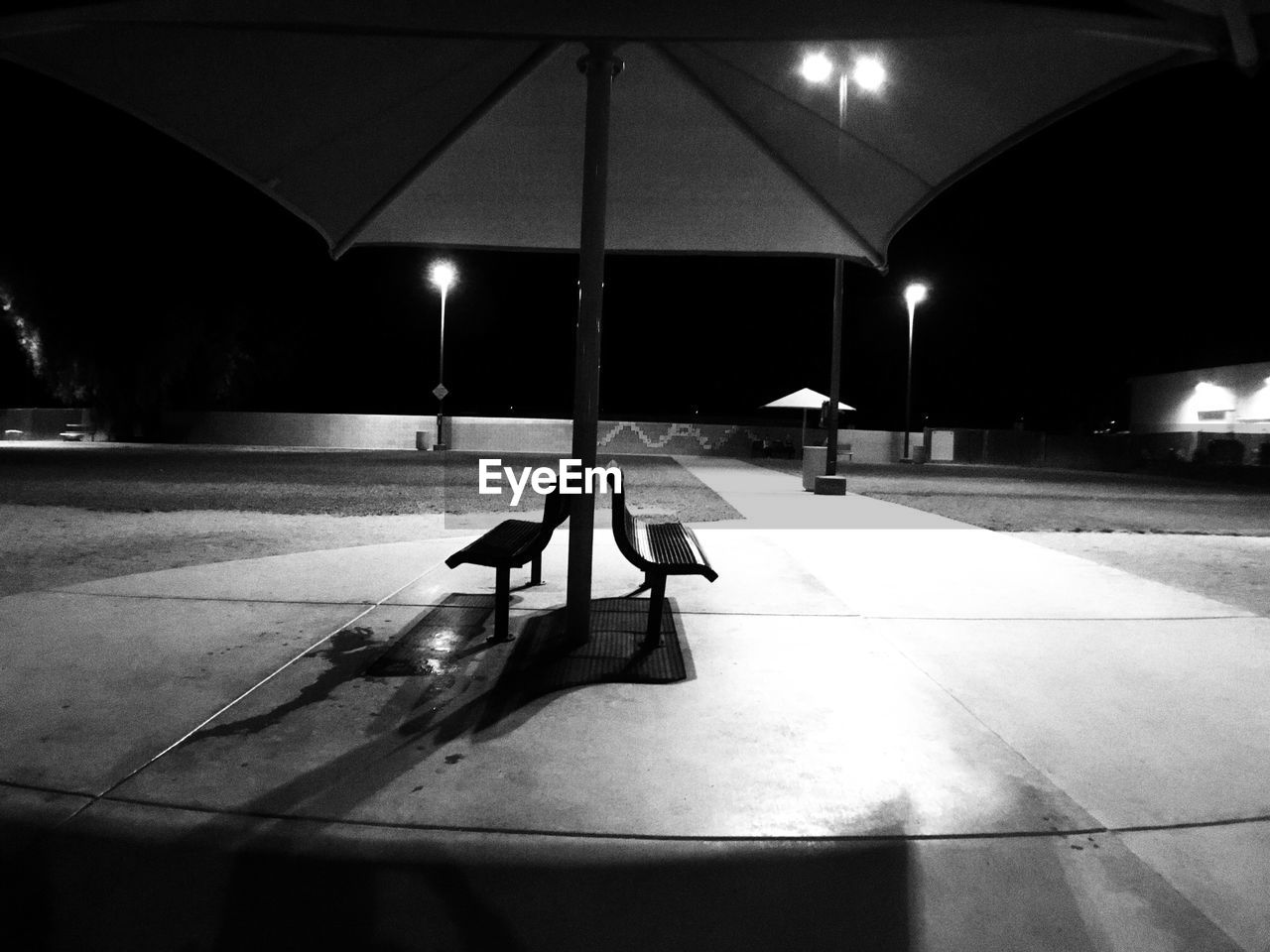 Illuminated empty benches in park at night
