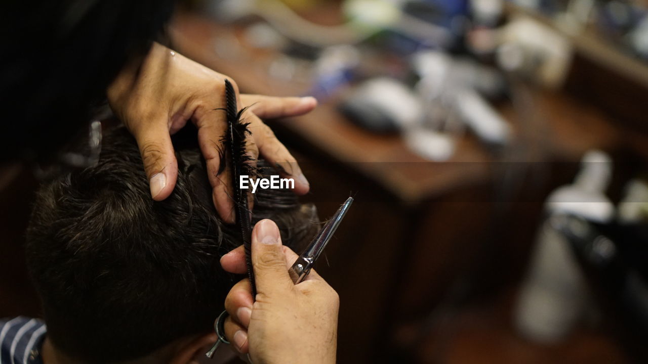 Close-up of barber giving haircut to client