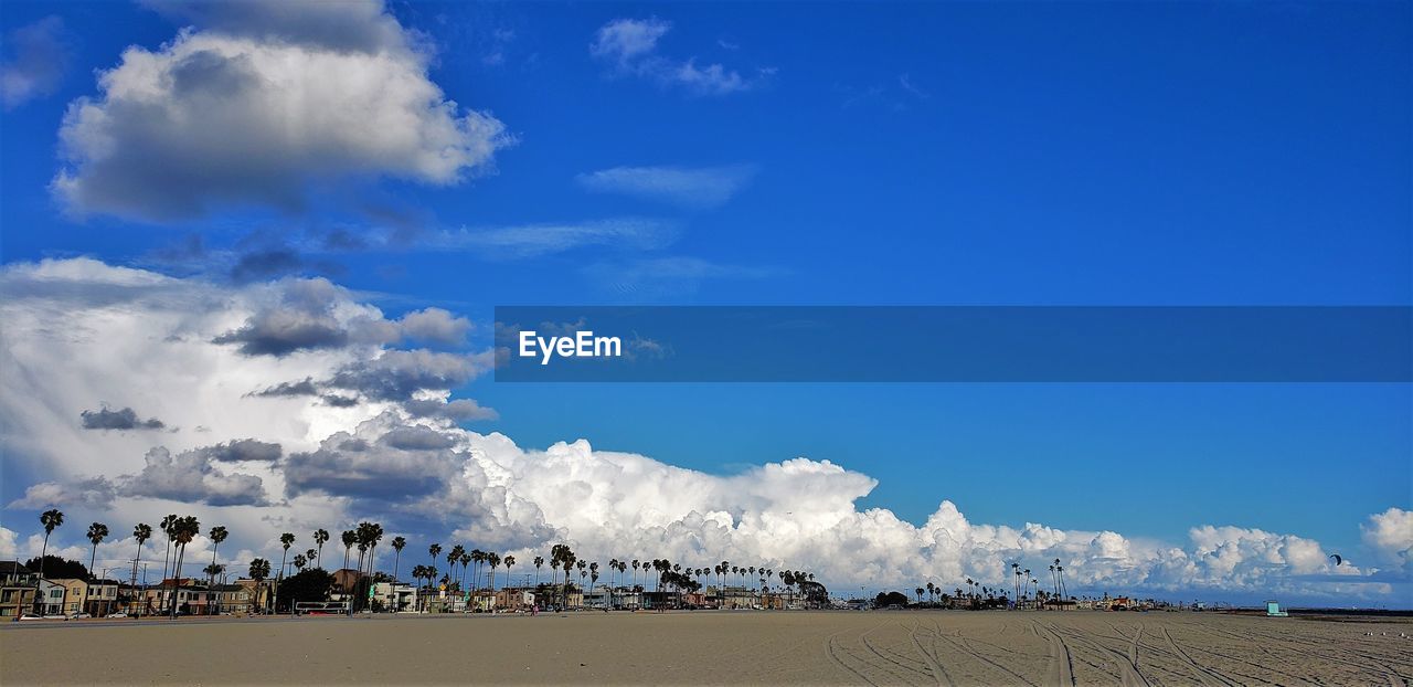 PANORAMIC SHOT OF PEOPLE ON BEACH AGAINST BLUE SKY