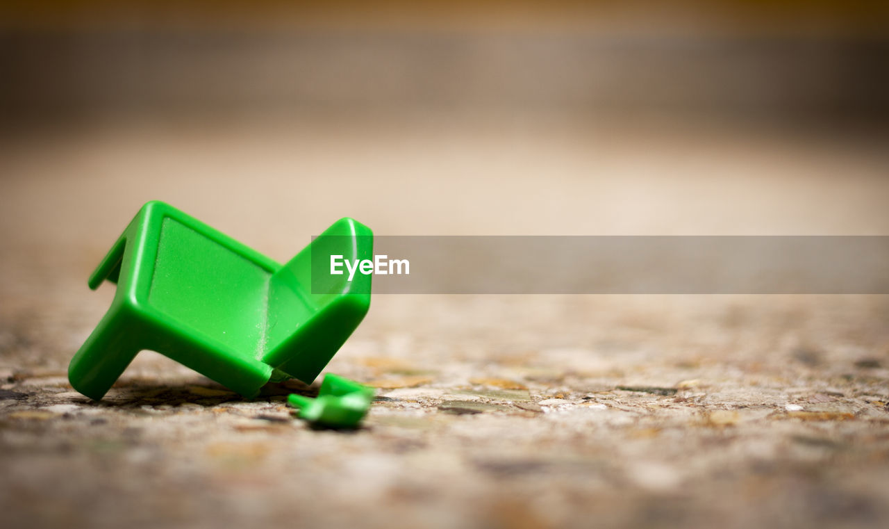 CLOSE-UP OF GREEN TOY ON WOODEN TABLE