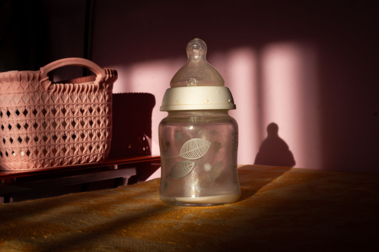 CLOSE-UP OF GLASS JAR ON TABLE AGAINST WOODEN WALL