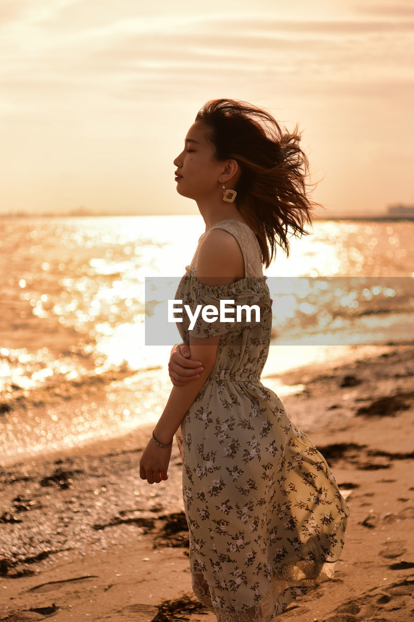 Side view of woman standing at beach