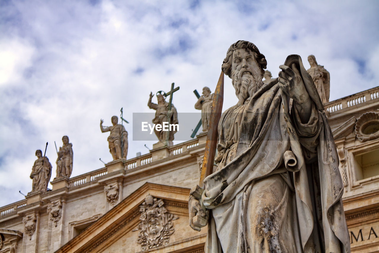 Low angle view of historical building and statue against cloudy sky