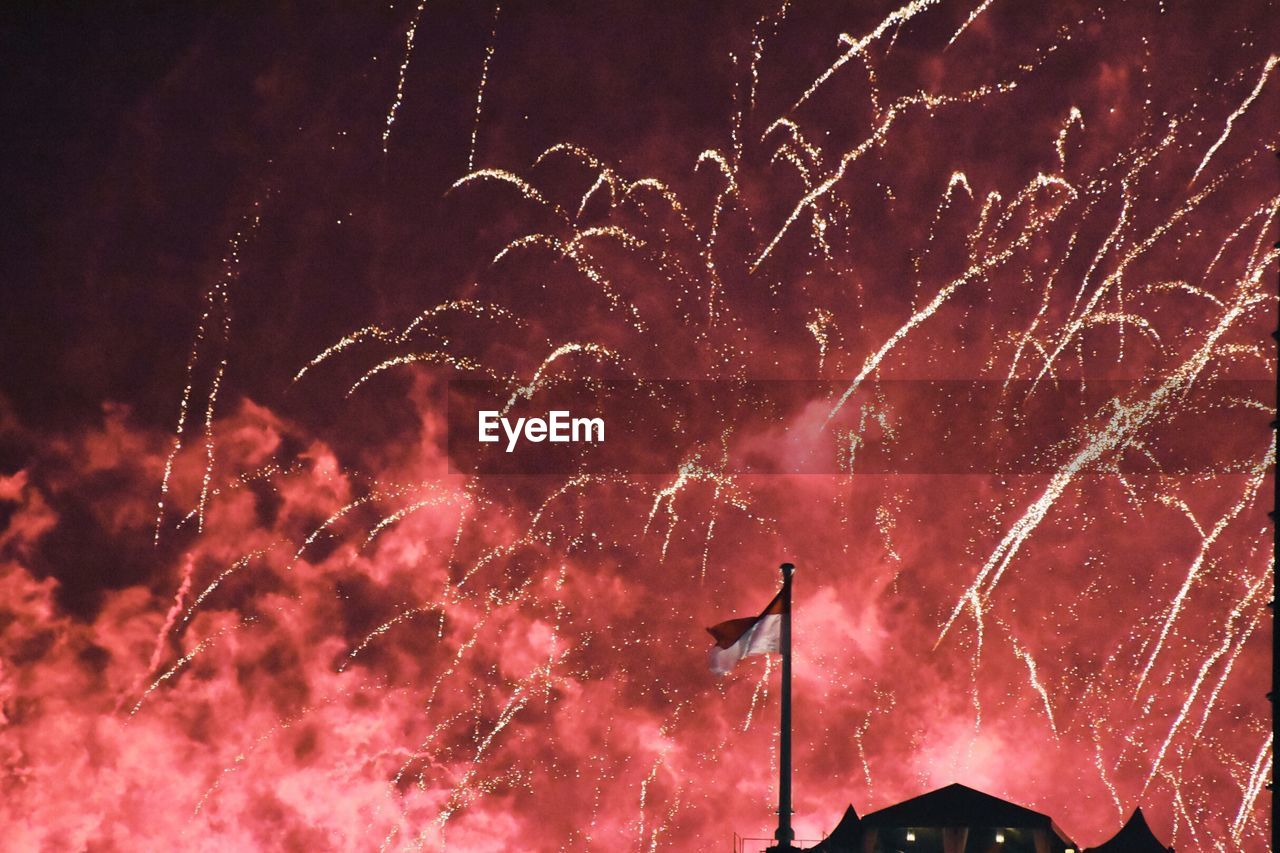 Low angle view of firework display over flag