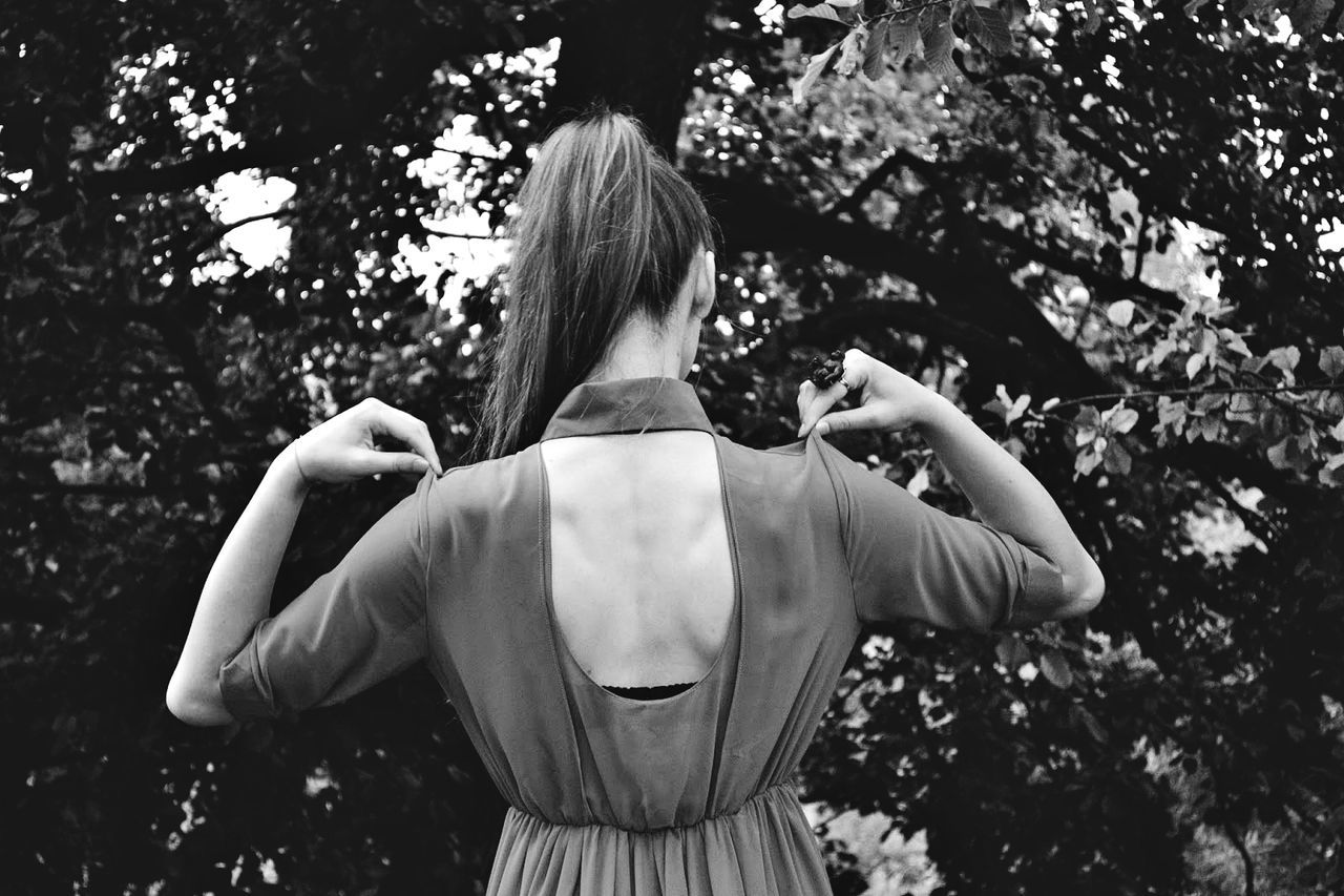 Rear view of young woman in dress against trees