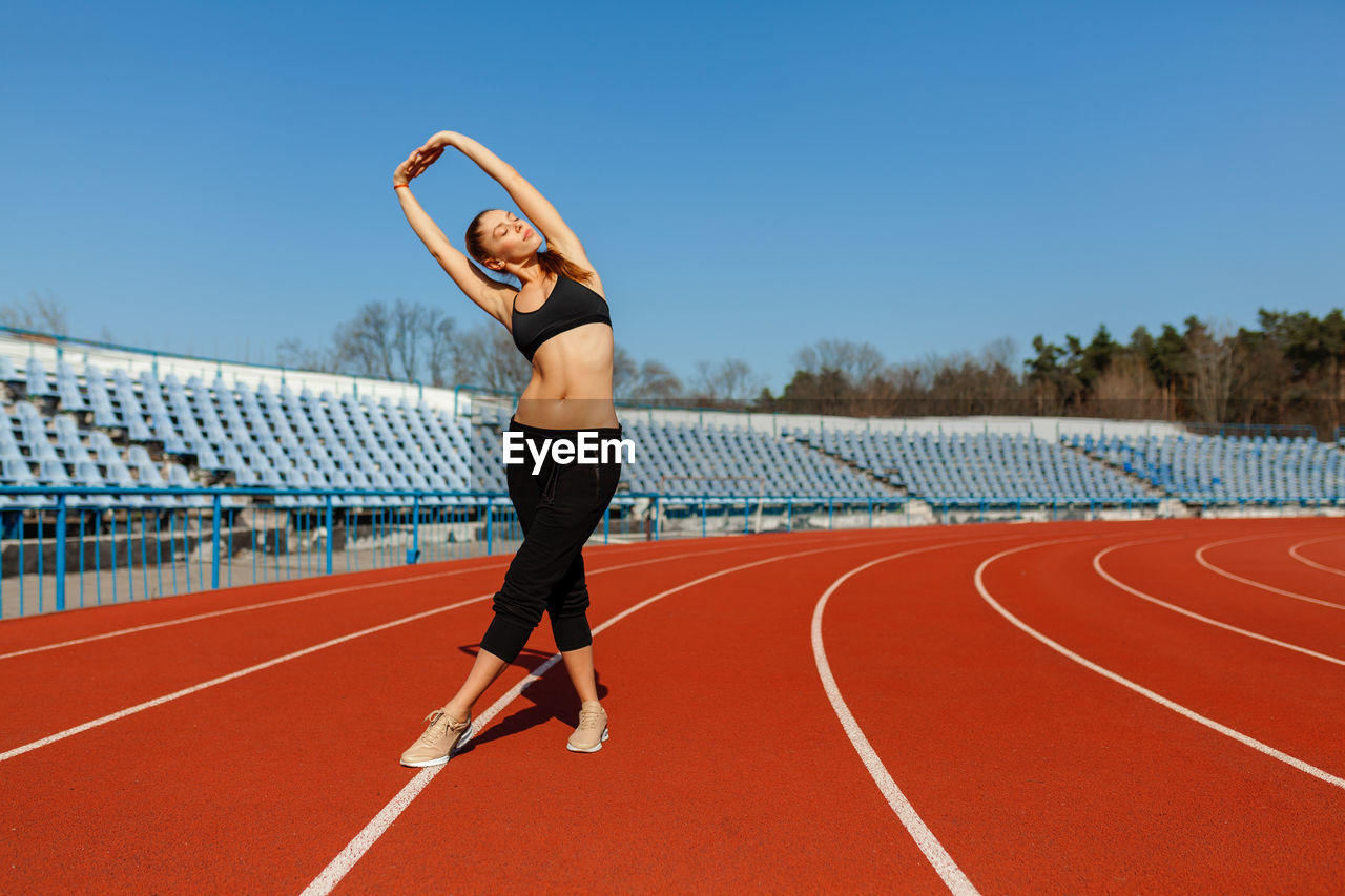Full length of woman exercising on sports track