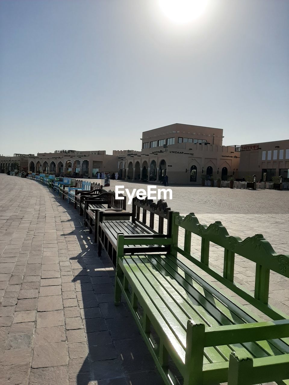 EMPTY BENCHES BY FOOTPATH AGAINST BUILDINGS IN CITY