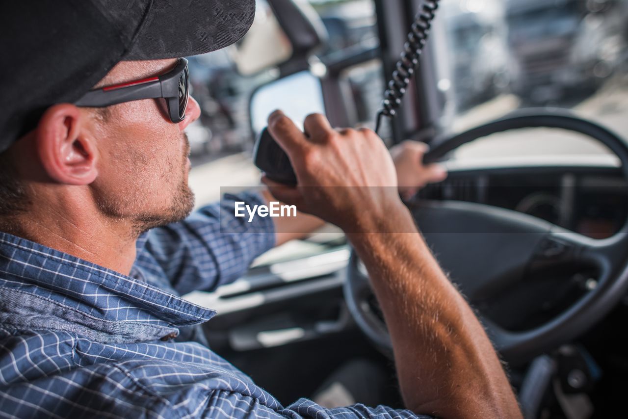 Man holding walkie-talkie while sitting in truck