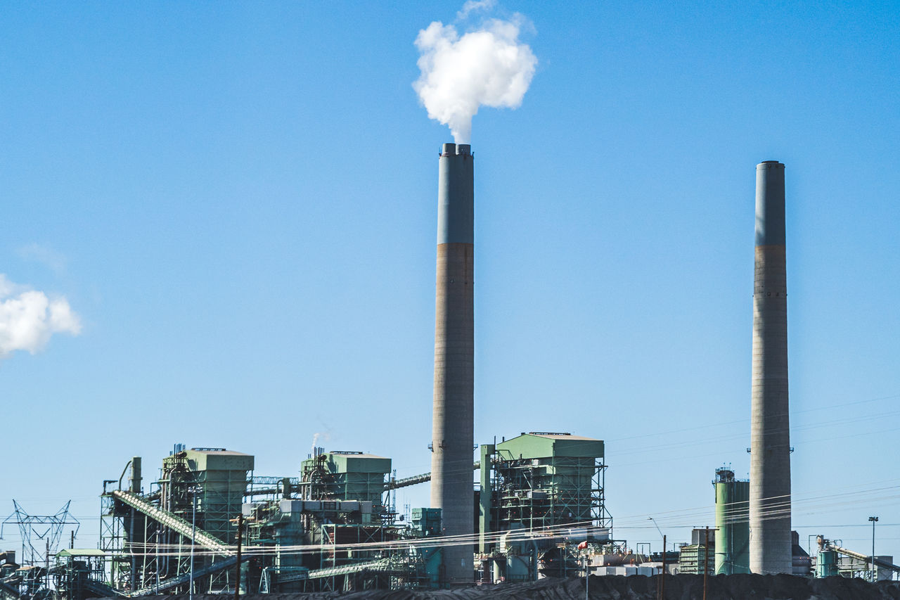 LOW ANGLE VIEW OF SMOKE STACKS AGAINST BLUE SKY