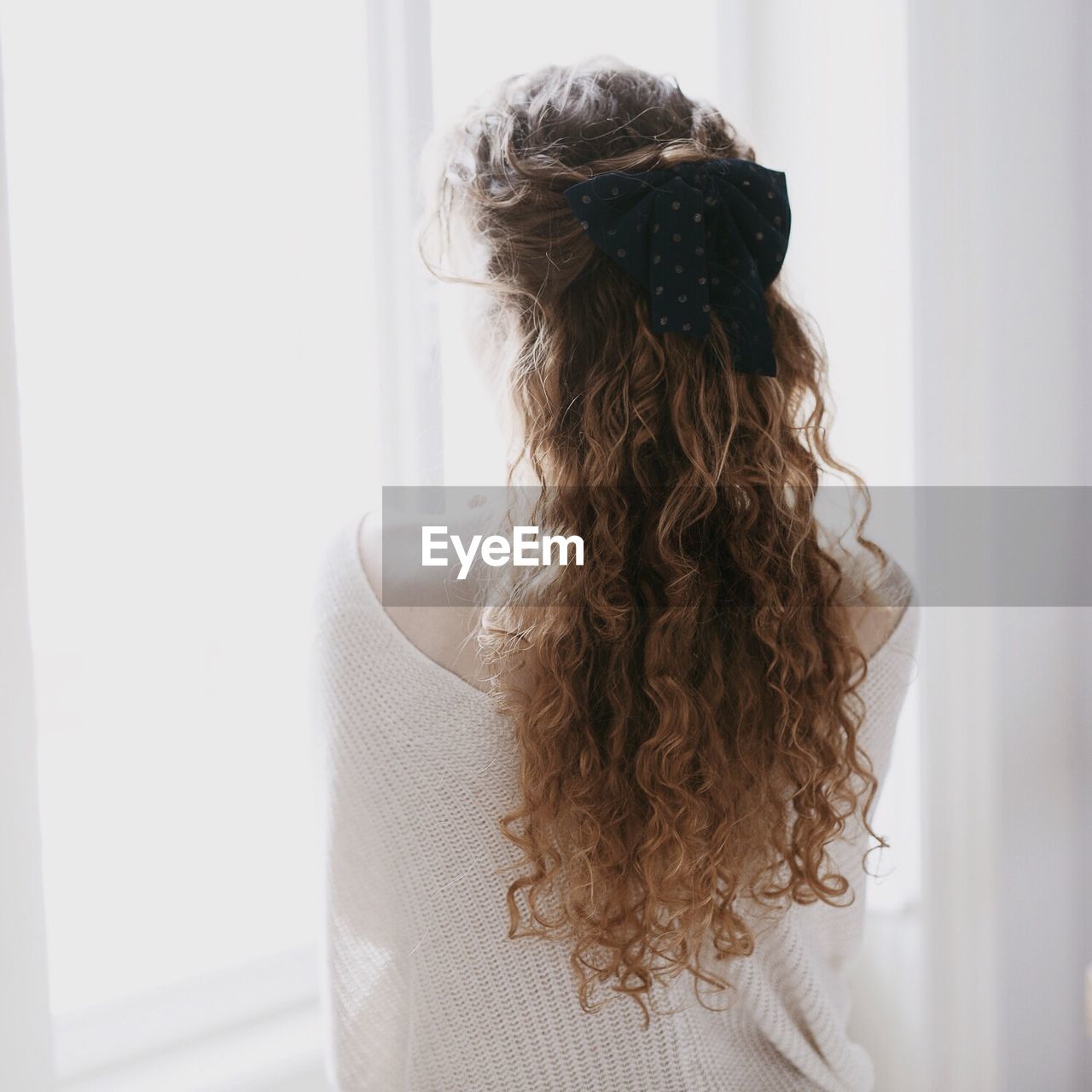 Rear view of woman with curly and long hair at home