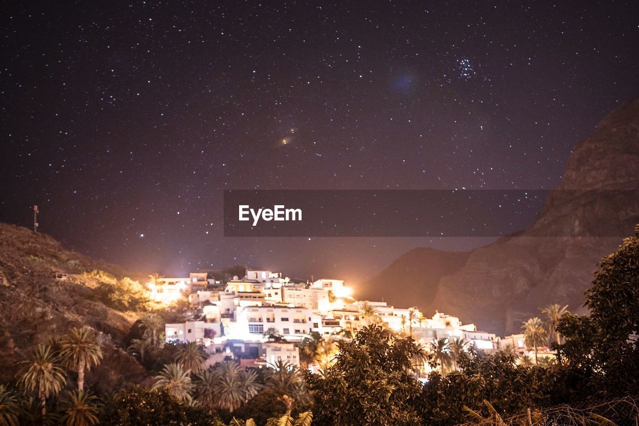 Illuminated buildings in city against sky at night