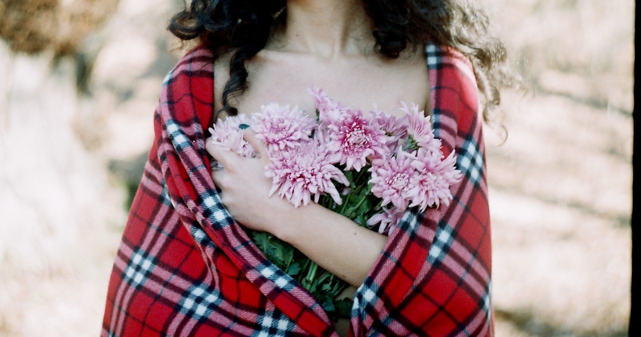 Midsection of woman with flowers wrapped in blanket