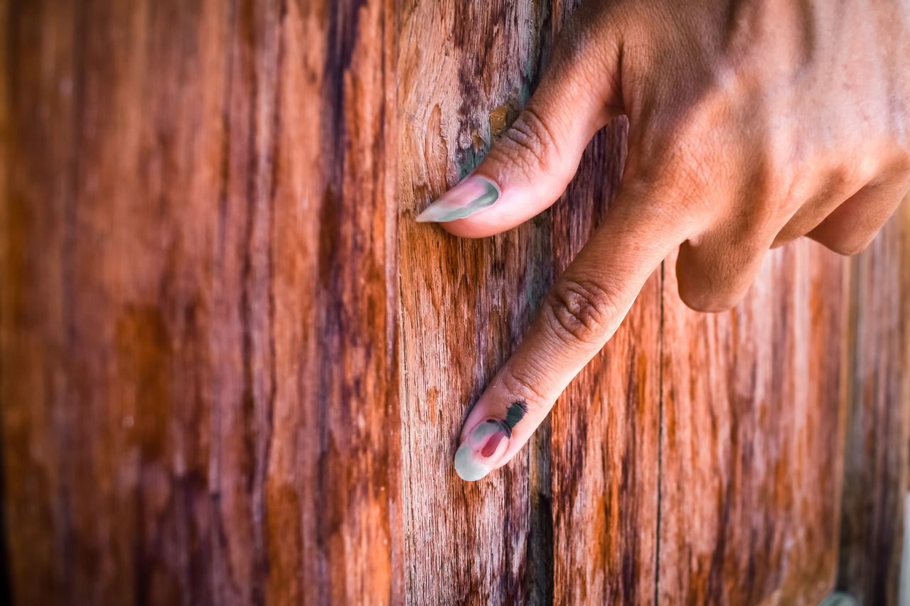 Cropped hand of woman hand on wooden wall