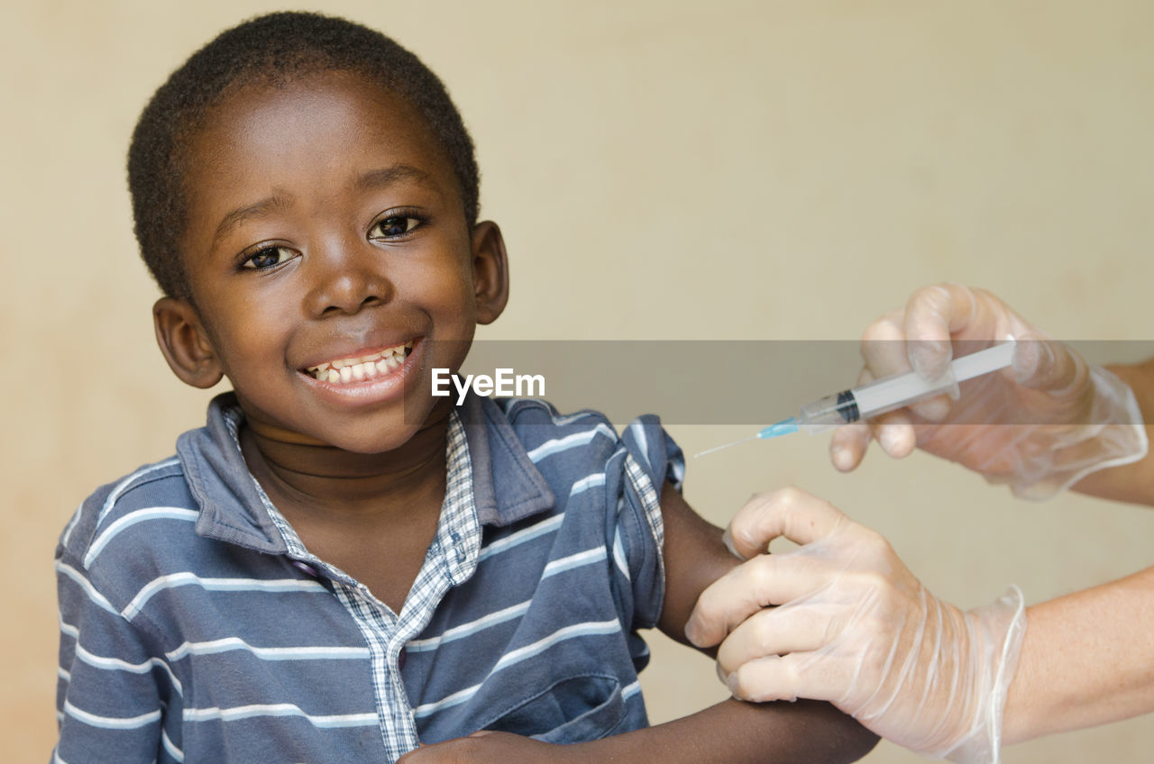 Cropped hands of doctor injecting smiling boy in hospital