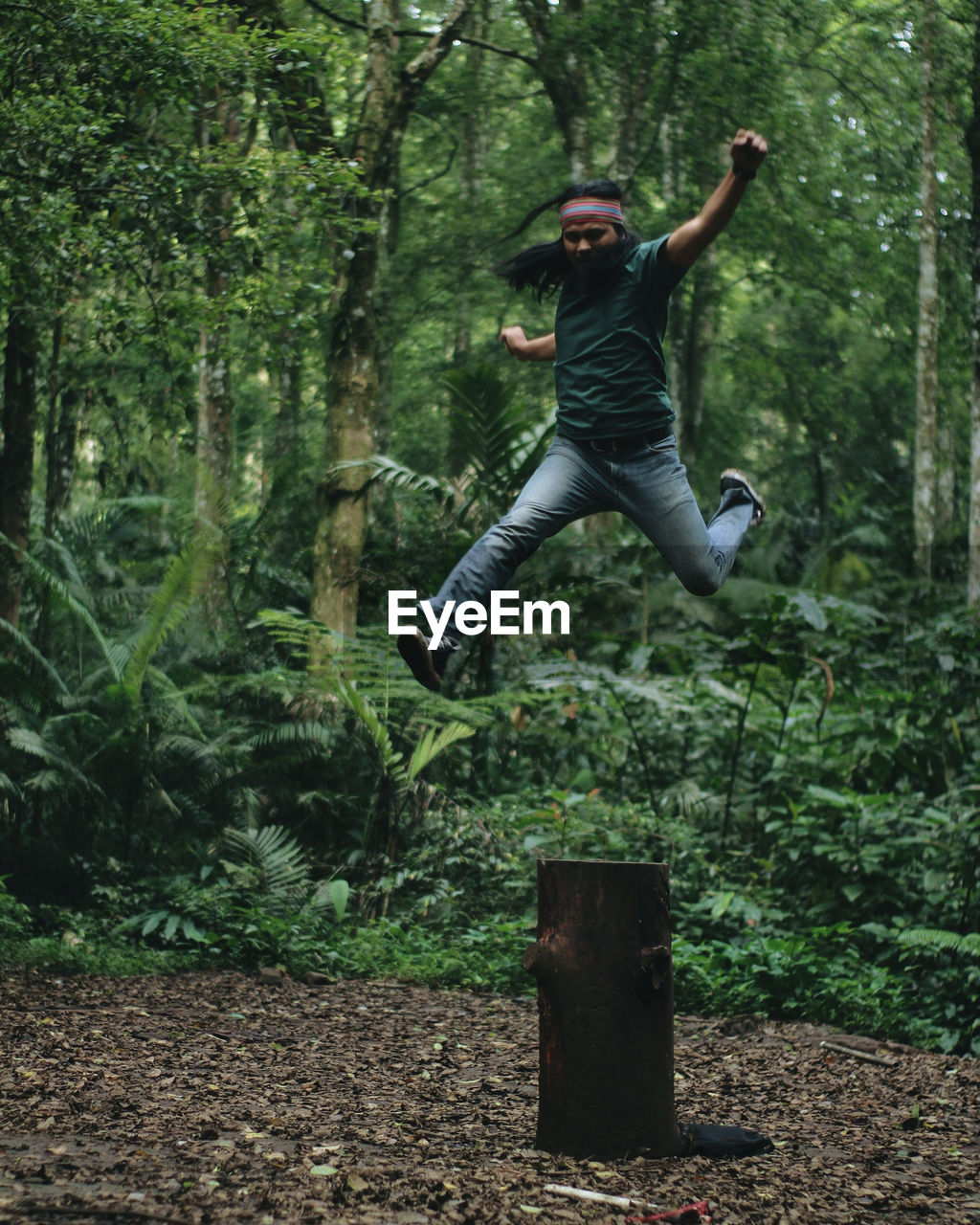 Full length of young man jumping in forest