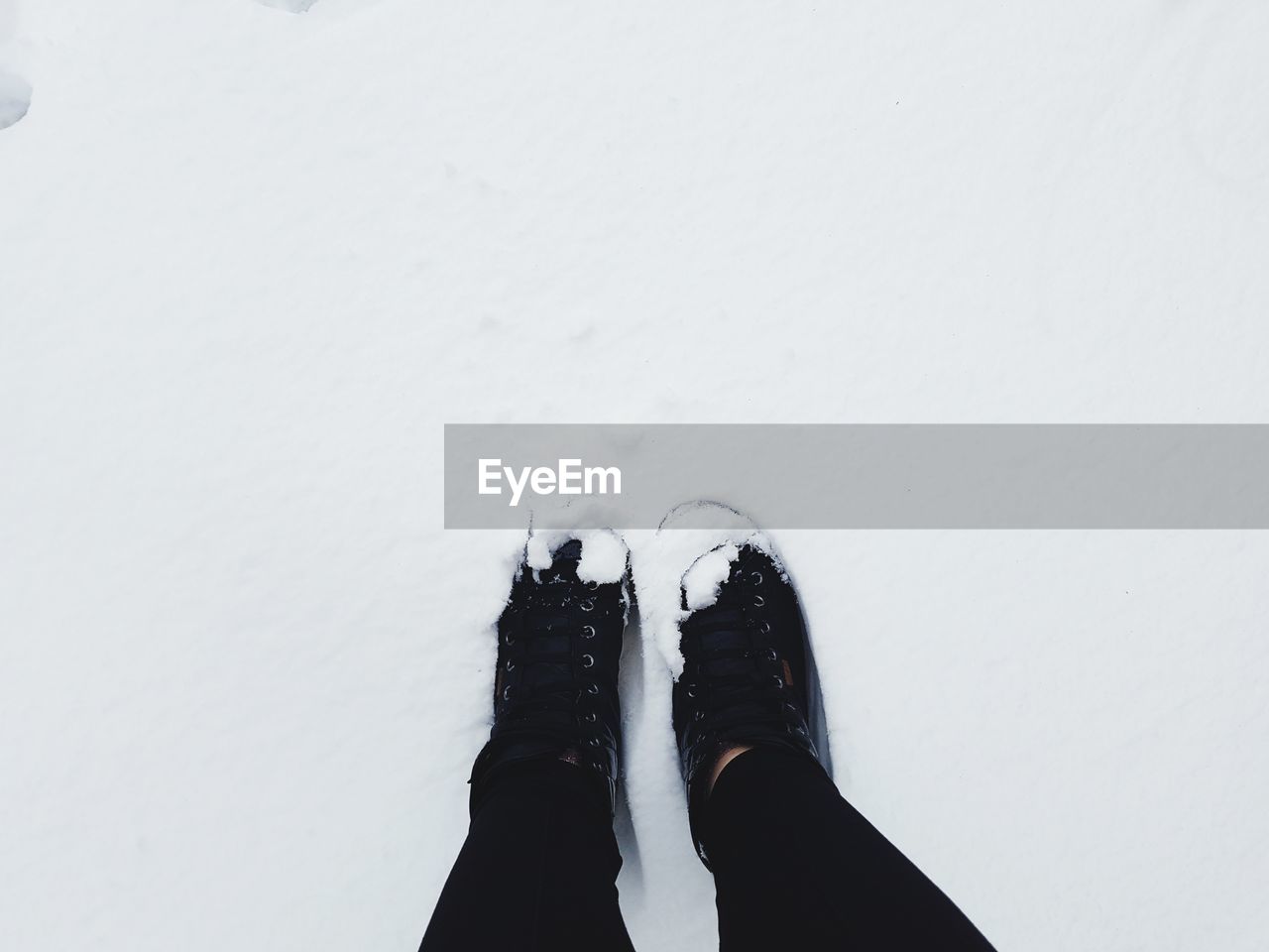 LOW SECTION OF PERSON IN SNOW ON SHOES