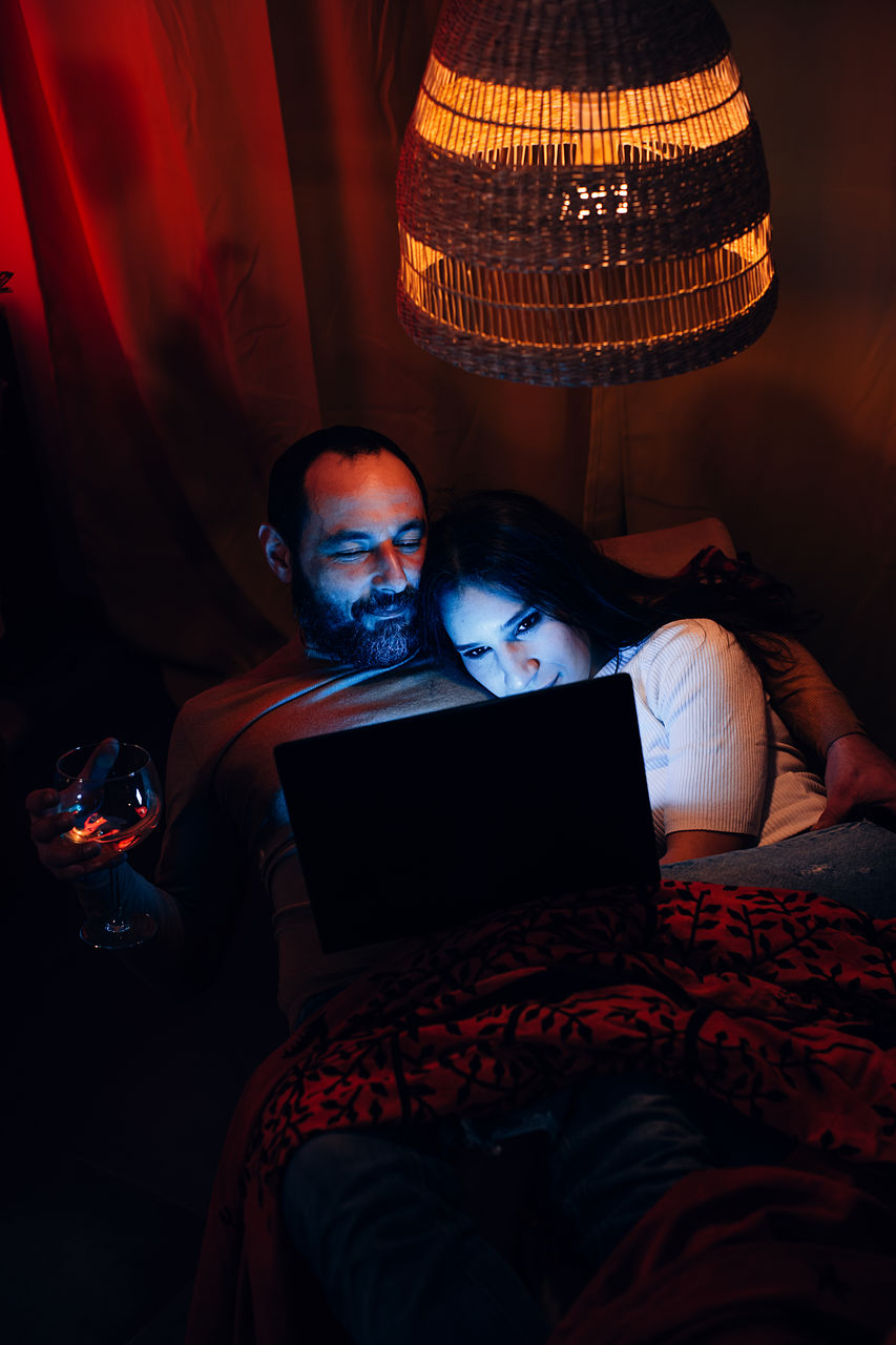 People chilling out at home at night watching a laptop. relaxed couple lying on a lounge chair