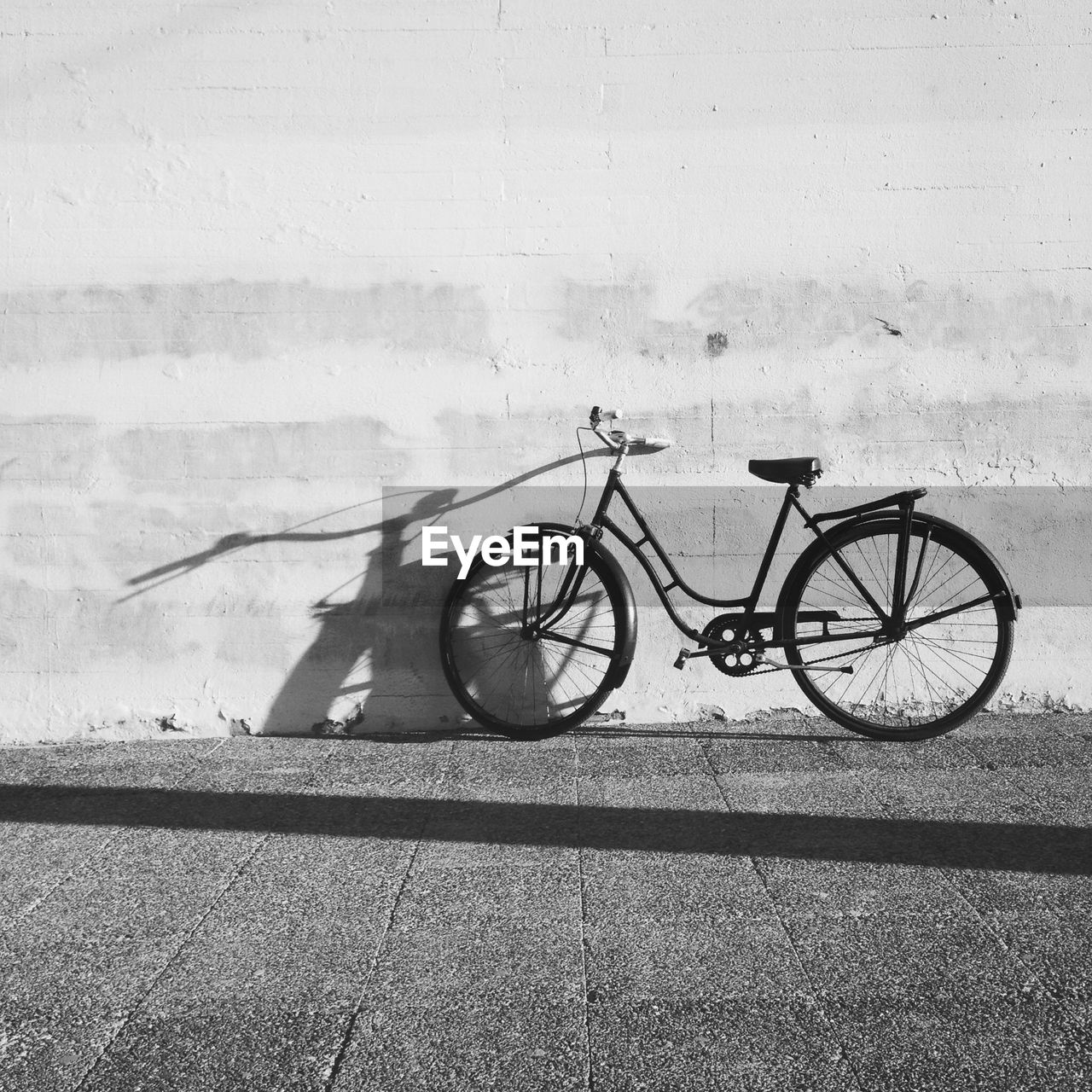 Bicycle parked against wall on street