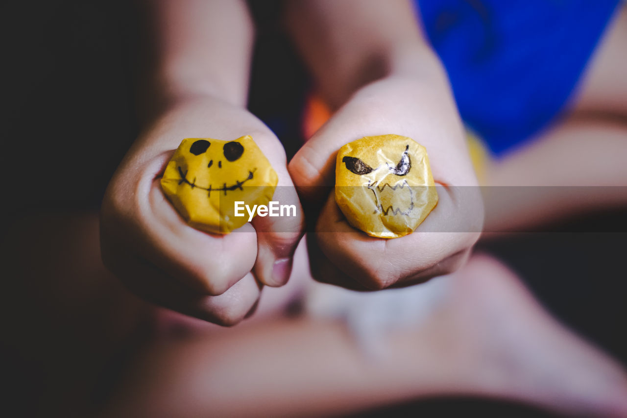 Close-up of child holding yellow scary faces