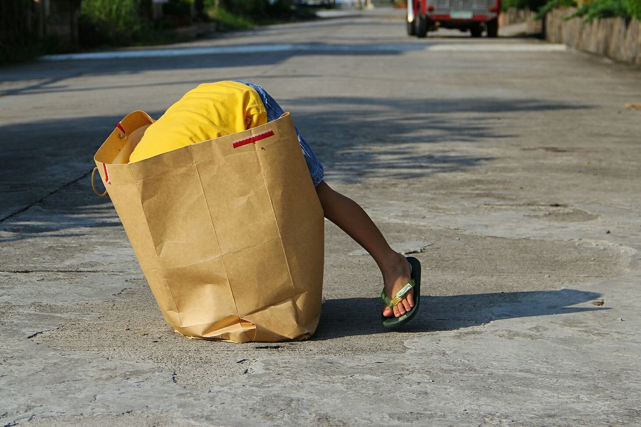 Boy searching in paper bag on street