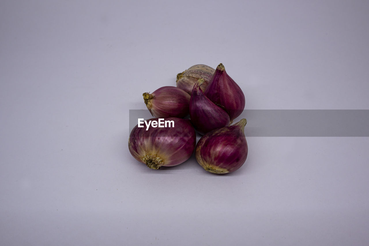 CLOSE-UP OF ONIONS AGAINST PURPLE BACKGROUND