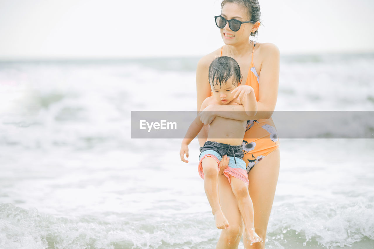 full length of young woman wearing bikini while standing at beach