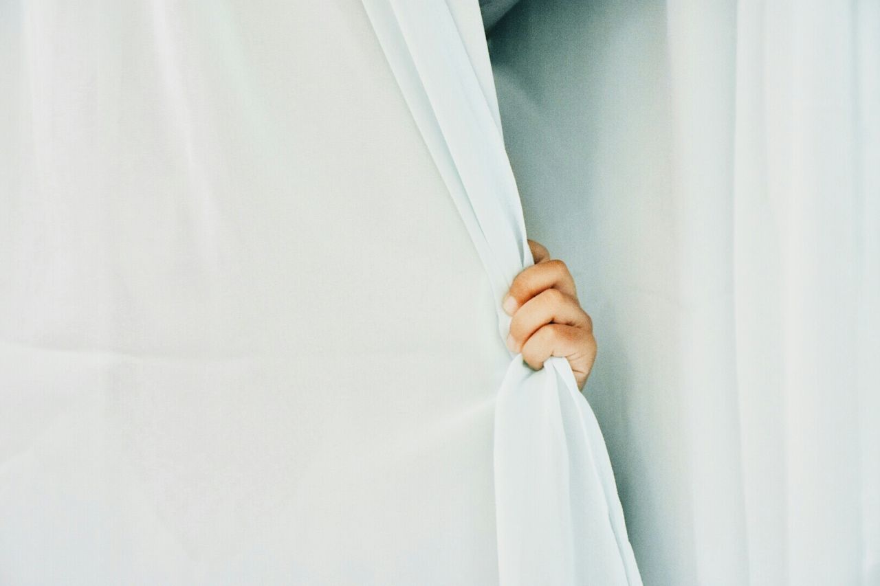 Close-up of persons hand holding curtain
