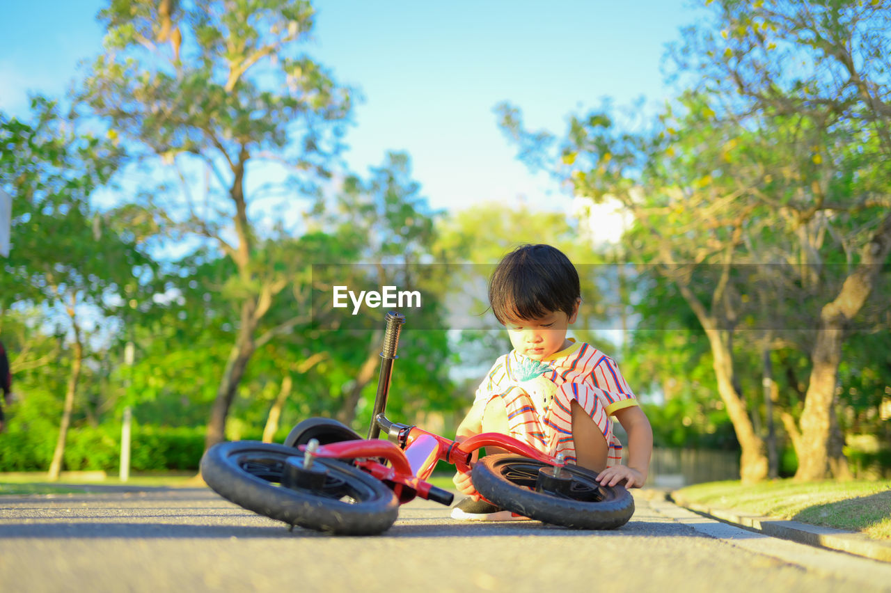 Boy sitting with bicycle on road