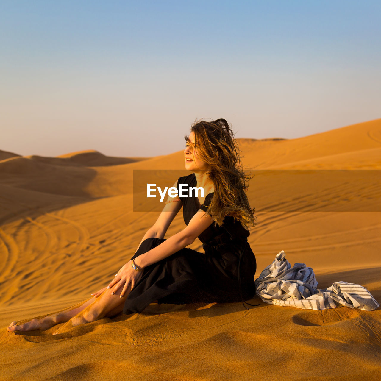 Beautiful woman sitting on sand in desert